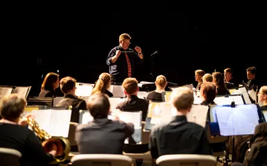 Band students playing instruments with conductor in front