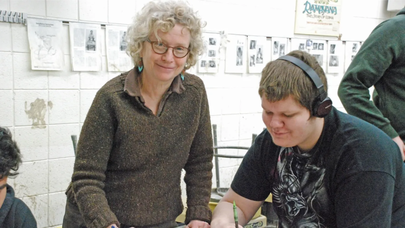 an instructor standing next to a student smiling  