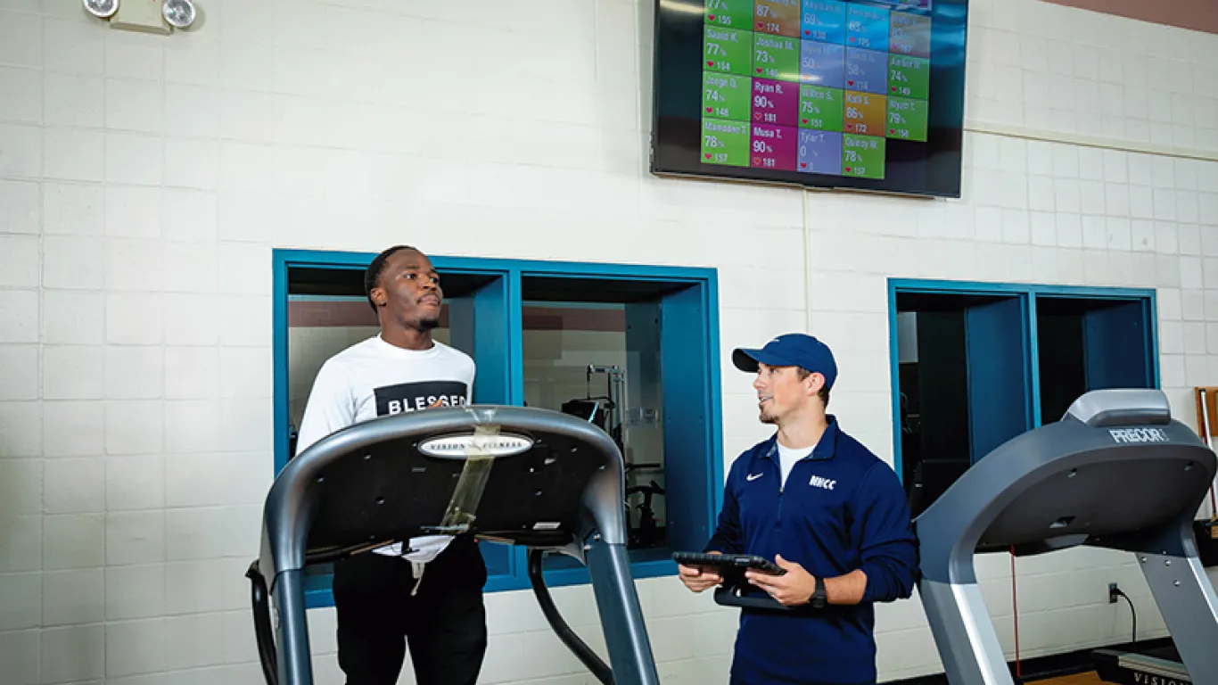 a student running on a treadmill next to an instructor 