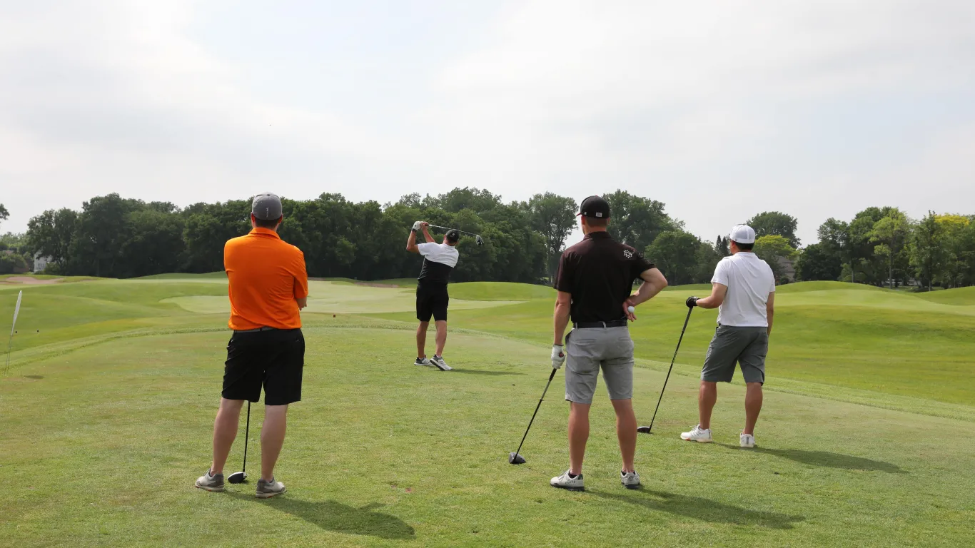 4 men teeing off on a golf course