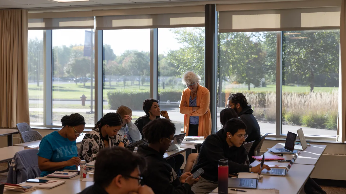 students talking with an instructor in a classroom 