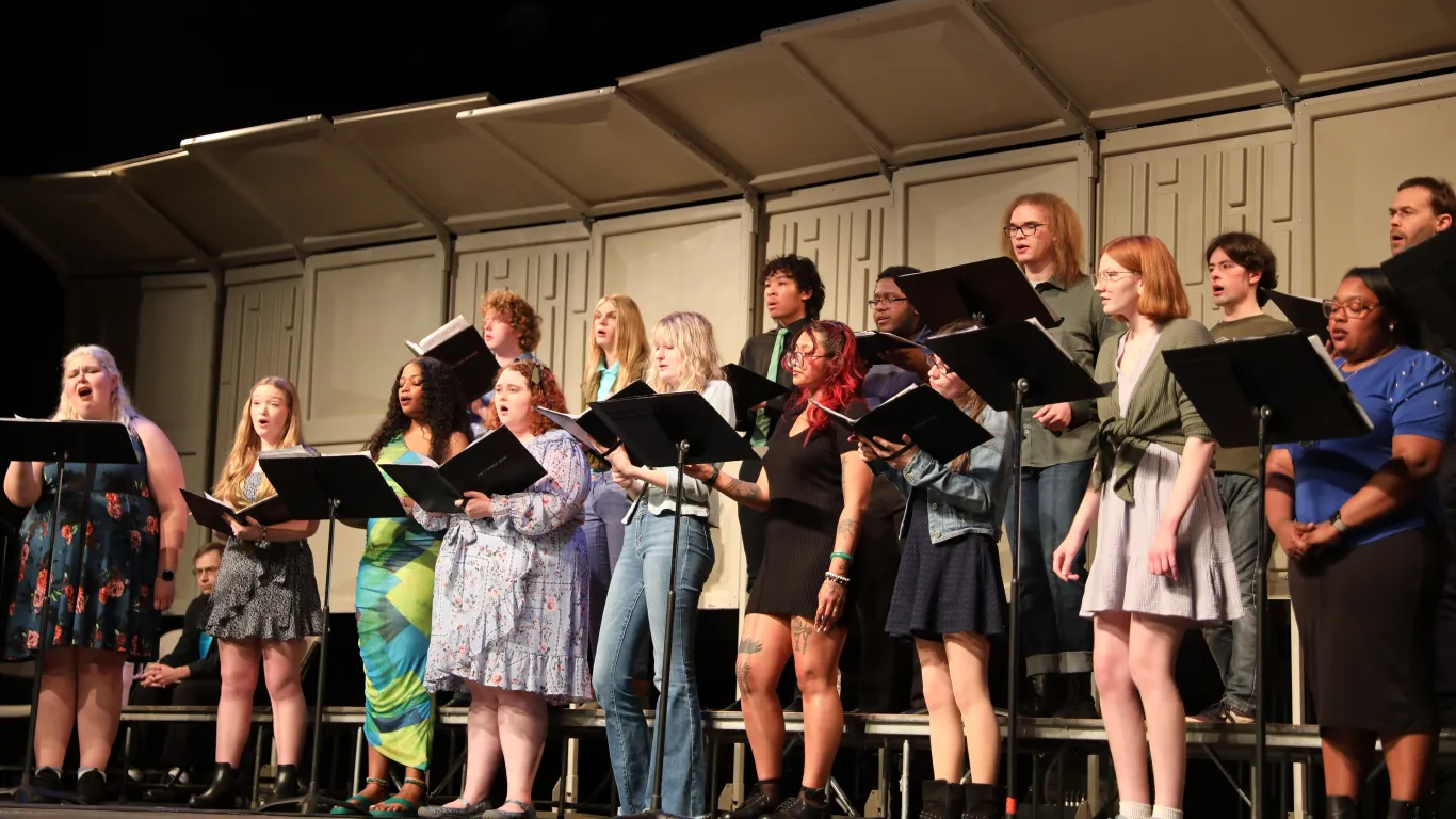 students standing on risers on stage singing 