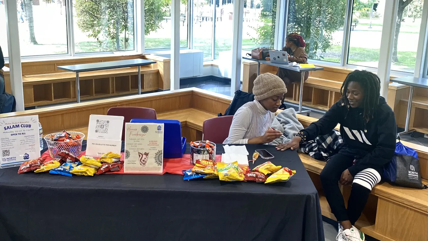 students at a table doing henna tattoos 