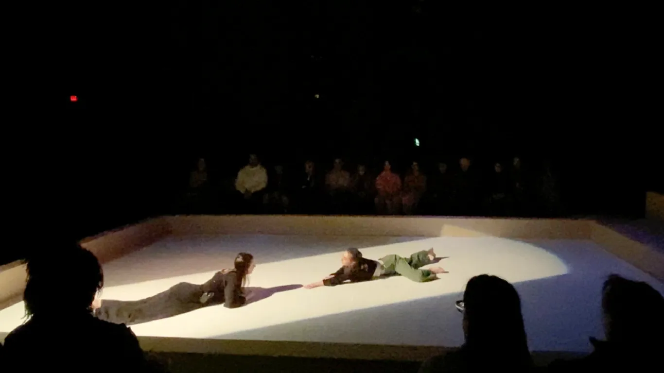 Two women in the play Antigone lying on the stage floor.