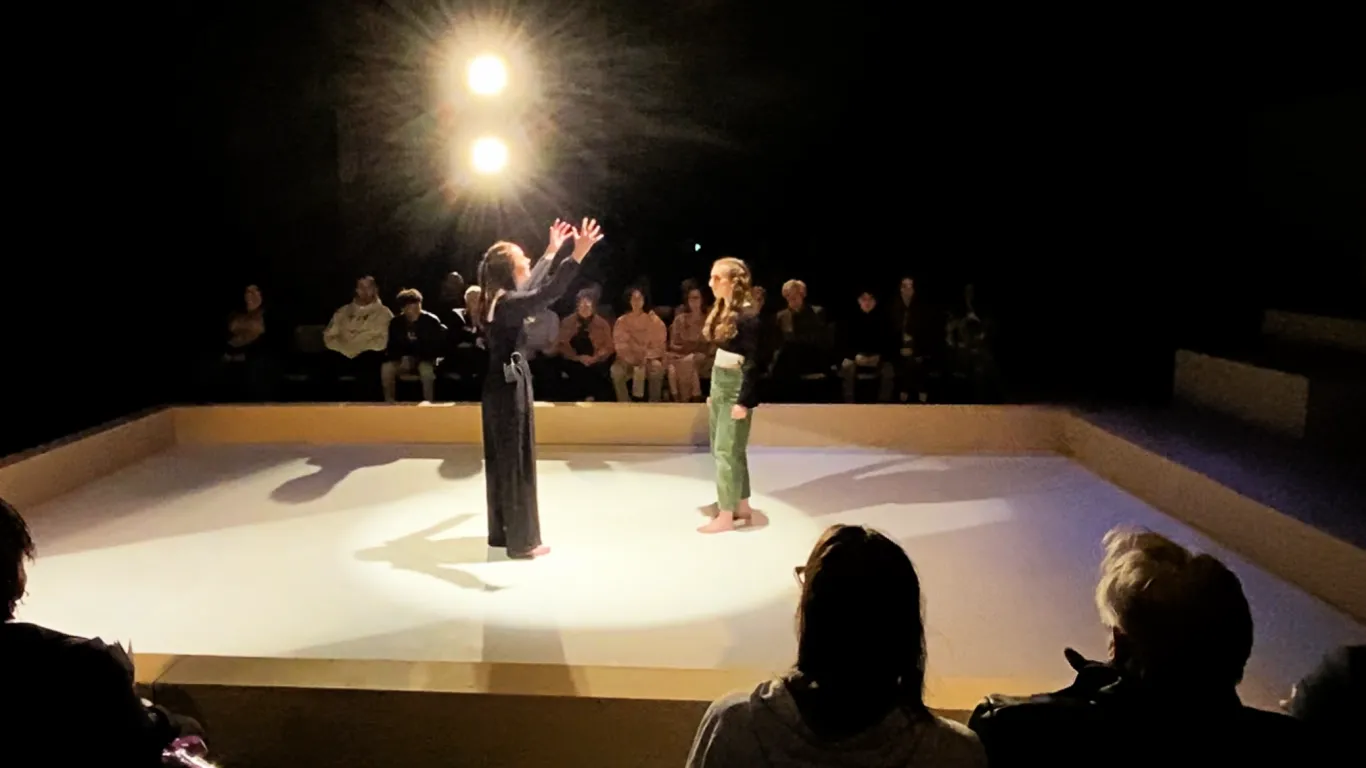 Antigone and Ismene facing each other on a stage.