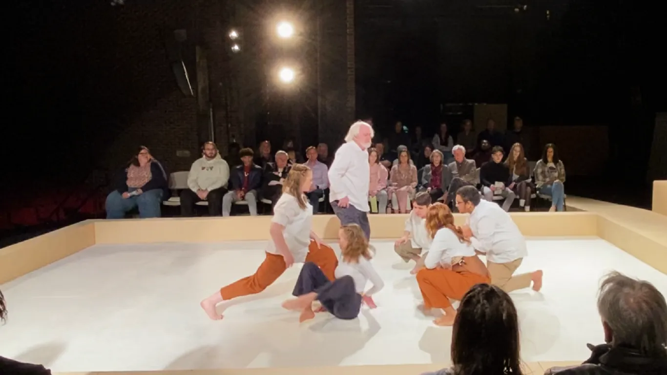 The chorus members in Antigone, standing and squatting in a circle. On a stage.