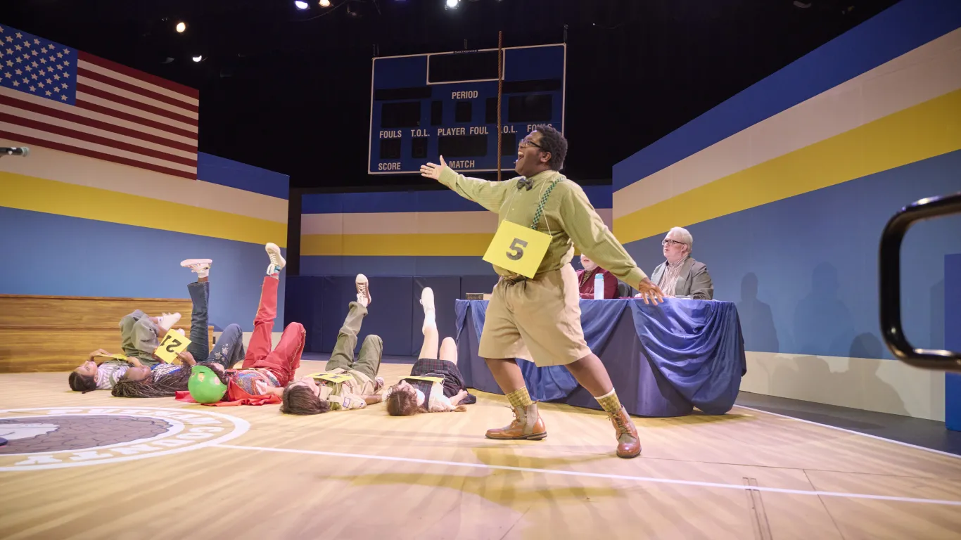 Actors performing on stage in the musical “The 25th Annual Putnam County Spelling Bee”
