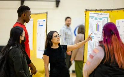 a student presenting research at a poster board 