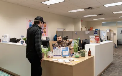 student talking to a staff member in a large office space