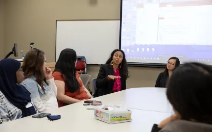 students and staff sitting around a table talking 