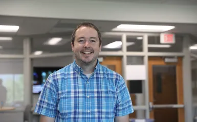 Monte Stewart, the new Director of Student Life, wearing a blue shirt in the Student Lounge