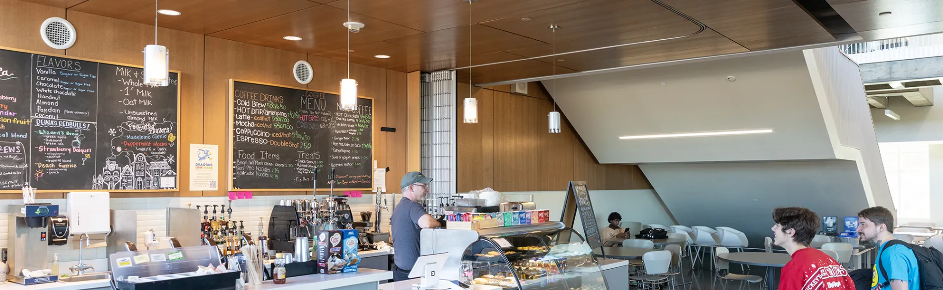 coffee shop with pastries behind glass and two students waiting