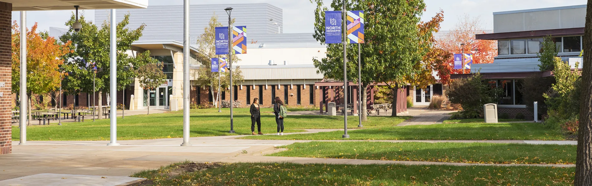 two students standing in a courtyard on a college campus