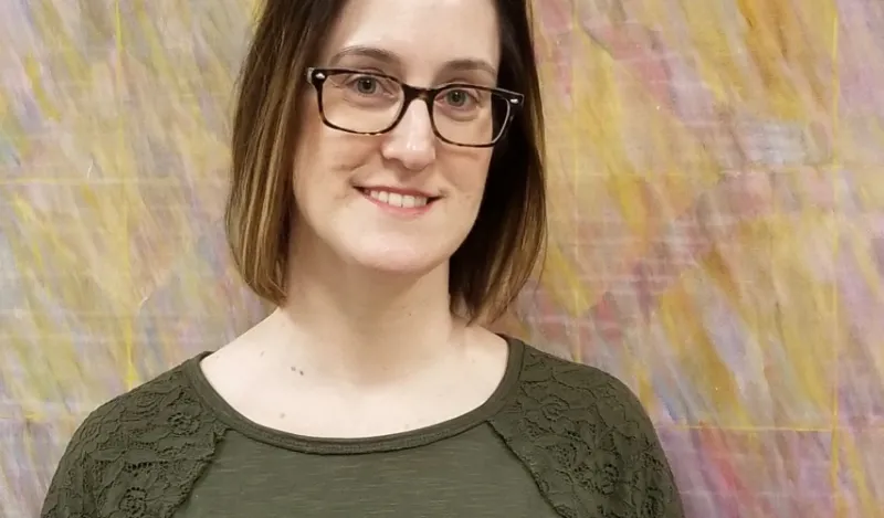 female student standing in front of a colorful piece of art