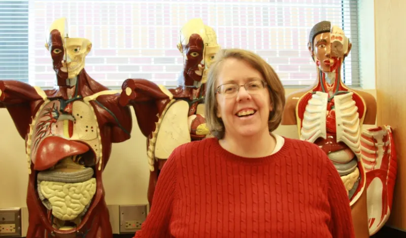 faculty member Dr. Tinna Ross standing in front of 3 anatomy models