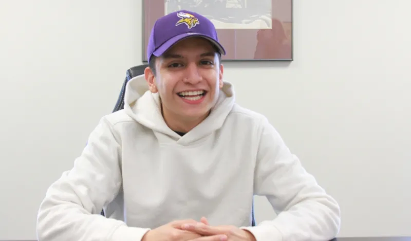 student Armando Morales sitting at a table smiling