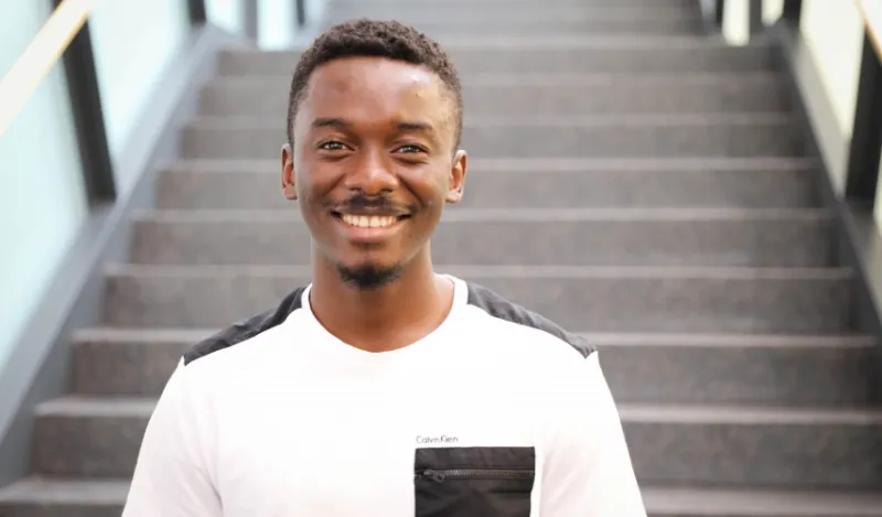 biology alumni Afeez Sodeinde standing in the grand hall of the center for business and technology smiling and facing the camera