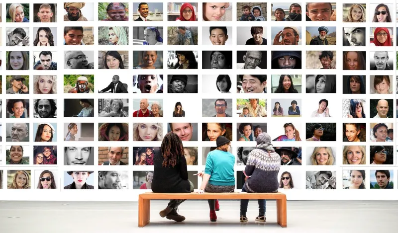 Image of students on a bench looking at photos on a wall. 