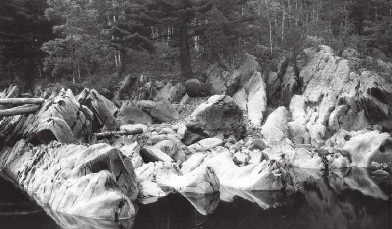 a black and white photograph of rocks by the water at Jay Cooke State Park