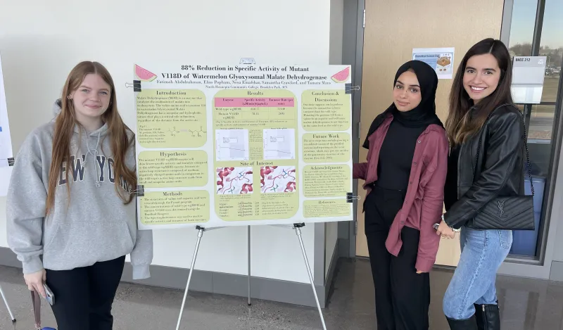 a photo of biology students next to their poster presentation