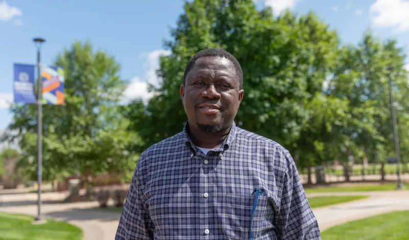 a photo of an adult male student, smiling in the courtyard