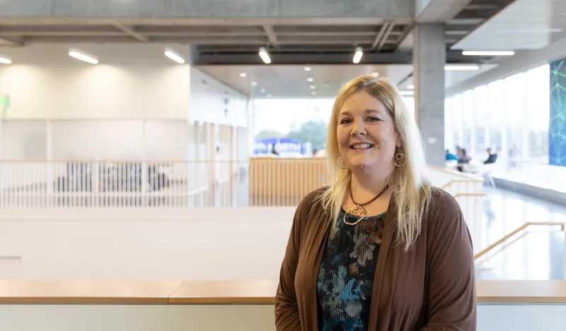 woman smiling with large atrium behind her 