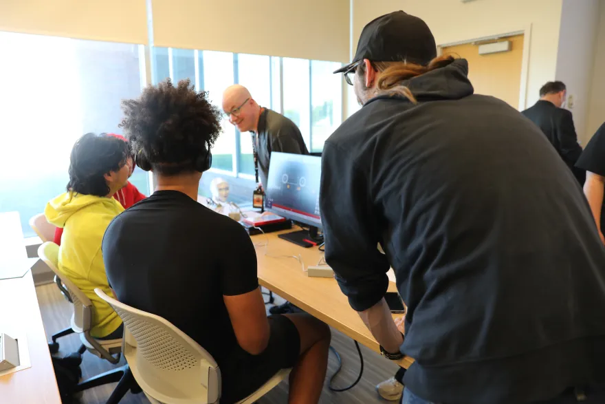 a photo of students playing video games with their teacher advising