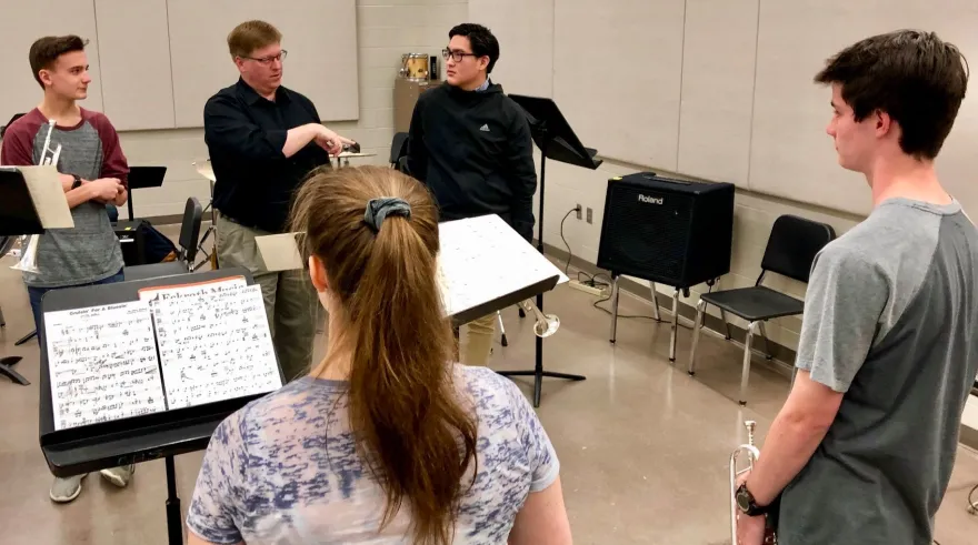 students talking with an instructor in a music classroom 