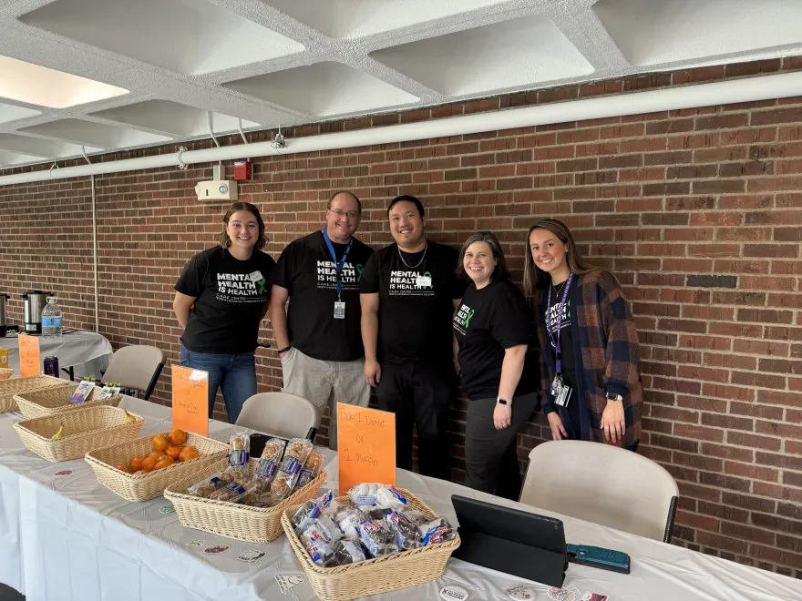 a photo of NHCC staff smiling in the hallway as a group