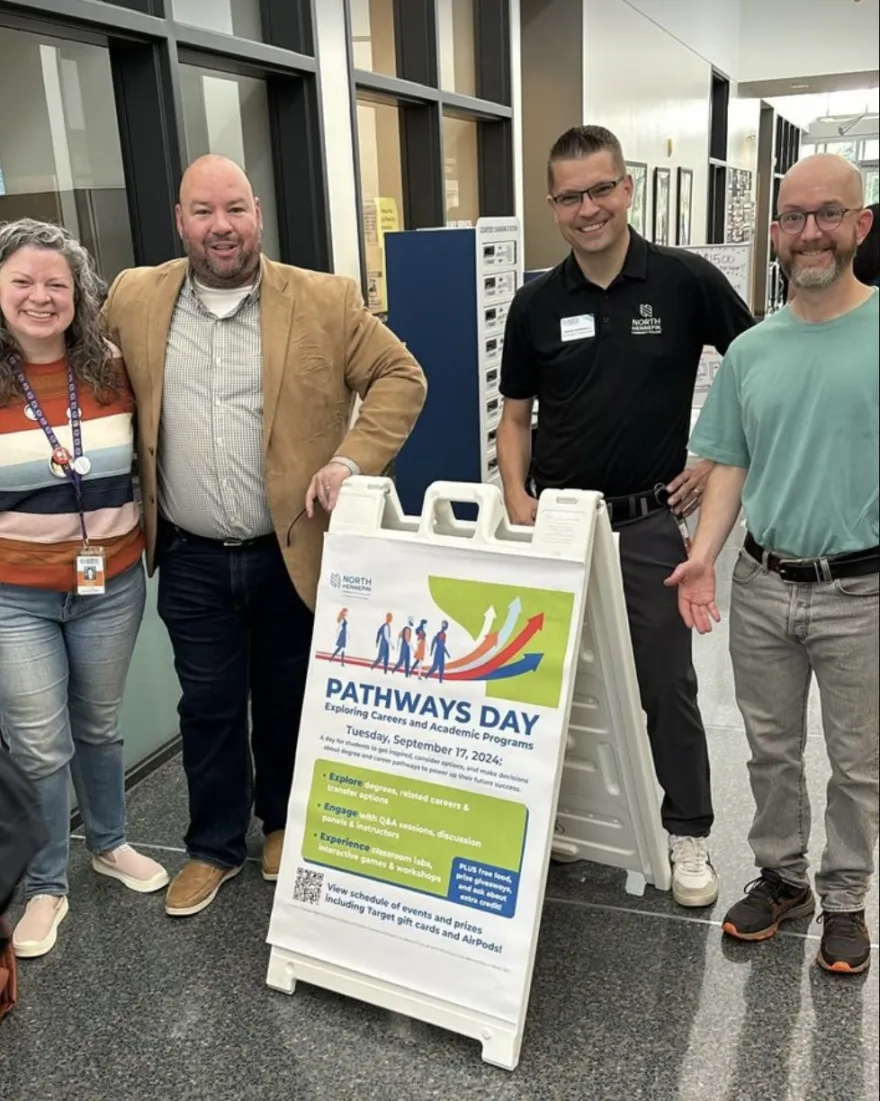 a photo of faculty and staff smiling while posing with a sign at Pathways Day 