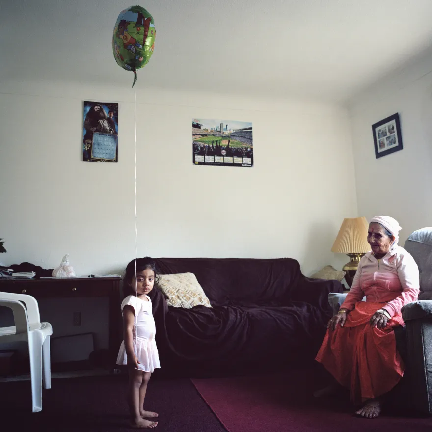 a photo of a little girl with her great-grandmother in the living room staring at the camera
