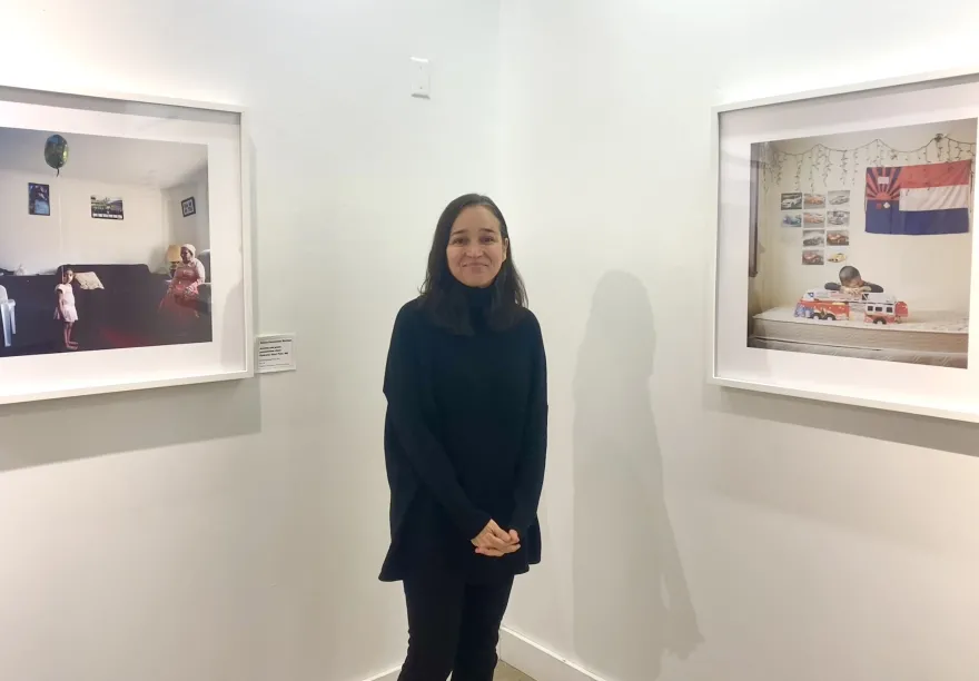 a photo of local artist, Selma next to her photographs hanging in the Art Gallery at NHCC