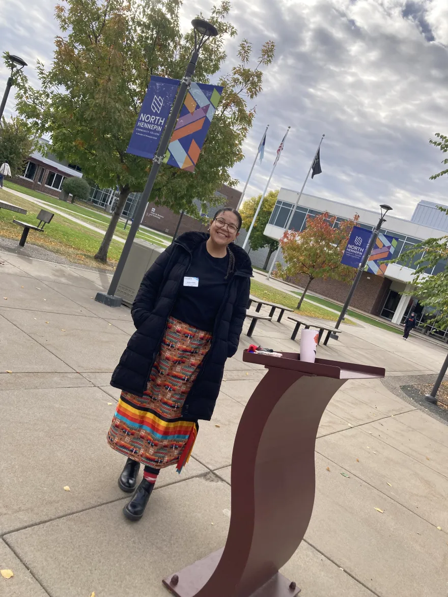 a photo of NHCC DEI employee, Justice Fisher outside in the courtyard before the smudging ceremony. 