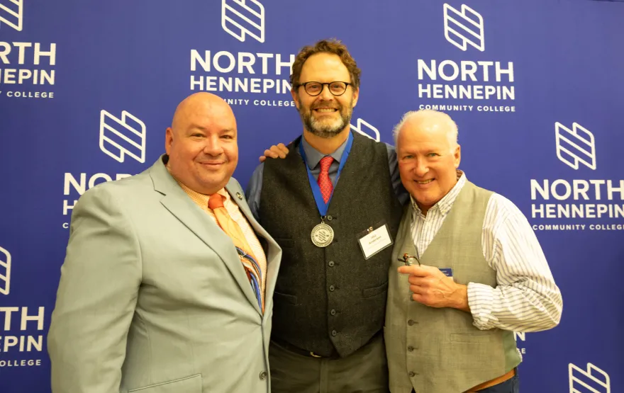 a photo of NHCC President, Rolando, standing next to NHCC alumni, Phil and NHCC Art Professor, Will. 