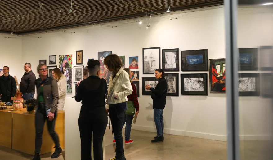 a photo of various guests viewing the high school art show pieces on display at NHCC in the gallery.