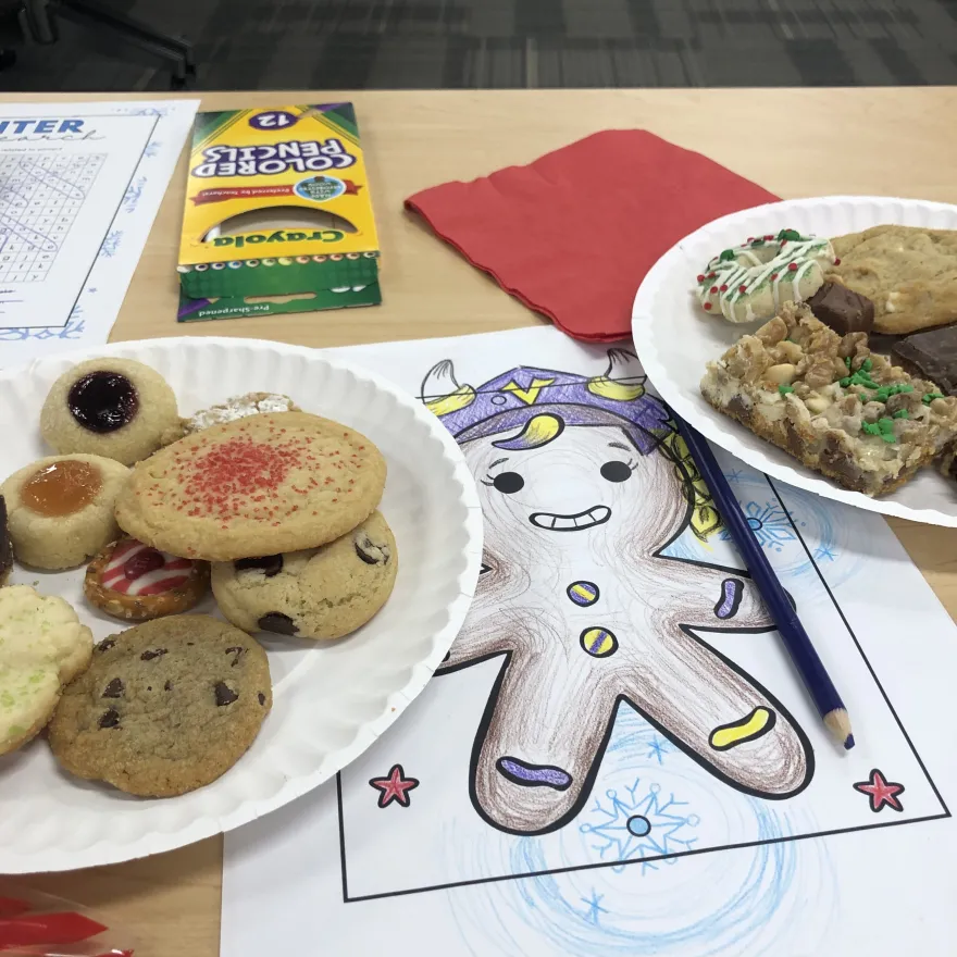 a photo of a coloring page and a plate of holiday cookies from our 2024 Employee Cookie Swap event at NHCC.