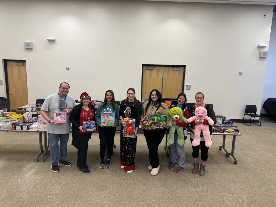 a group photo of NHCC employees and student volunteers with children's toys at the 2024 Toy Express event on-campus. 