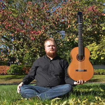 man sitting outside holding a guitar