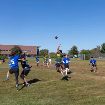 group of students on the field, football in the air