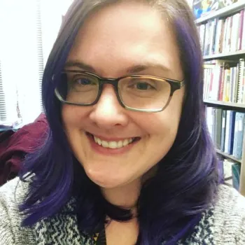 woman smiling in front of a book shelf