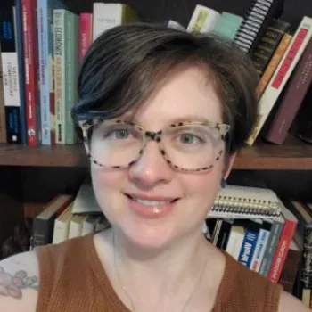 woman smiling wearing glasses in front of a book shelf